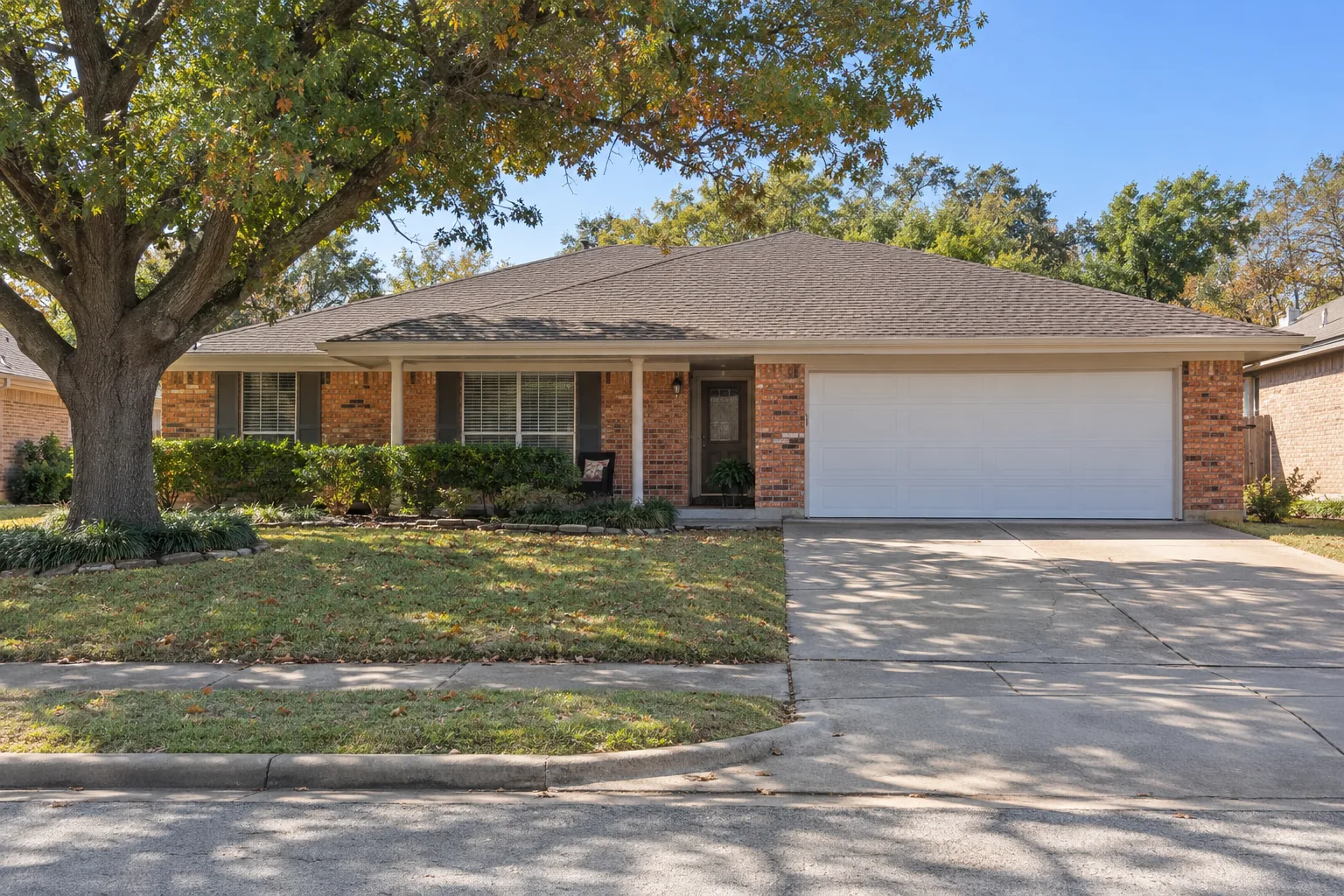 Brick ranch home on a wooded lot under tall pines in Conroe, TX