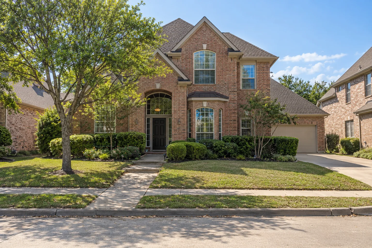 Two-storey 1990s brick home with a side-entry garage in Plano, TX